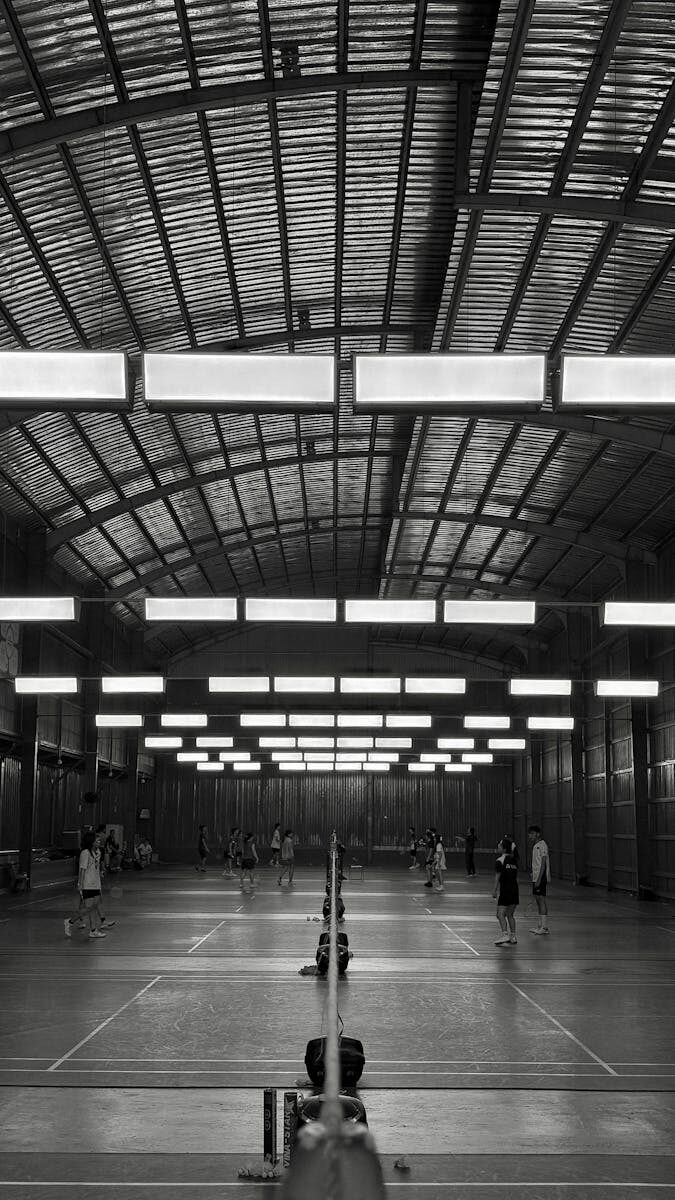 Monochrome view of a busy indoor badminton court in Vietnam.